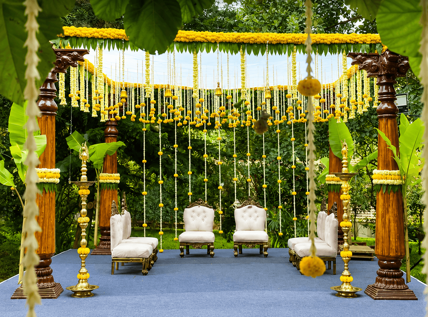 Traditional wedding mandap with carved wooden pillars, marigold and jasmine garlands, and ceremonial seating decorated by Jayram Catering